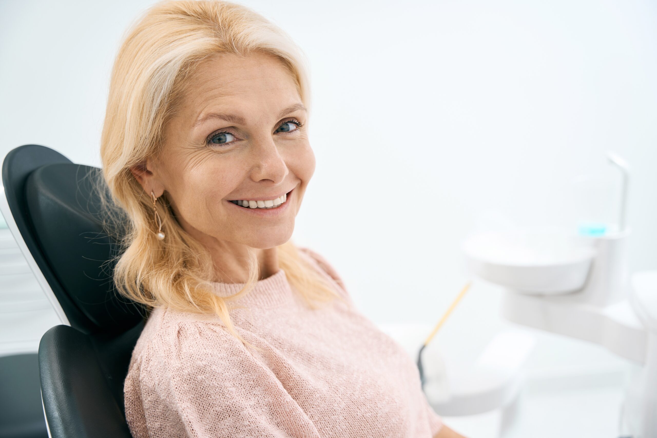 A woman smiling and showing her implant-supported dentures