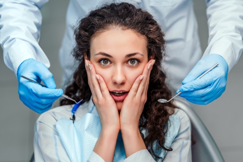 Woman in dental chair with fearful look on her face due to dental phobia.